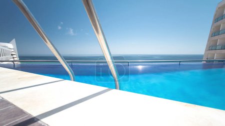 Hotel swimming pool with sunny reflections and blue water timelapse, view on the beach of Sesimbra, Portugal