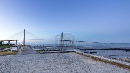 Téléchargez les photos : Vasco da Gama Bridge over the Tagus river is the largest bridge in all Europe timelapse from day to night transition when lights turn on. Lisbon, Portugal - en image libre de droit