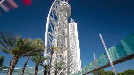 Téléchargez les photos : Hôtel Tour avec palmiers et drapeaux dans le Parc des Nations timelapse hyperlapse Il est de 145 mètres de haut construit sur le Tage. Ciel bleu à Lisbonne, Portugal - en image libre de droit