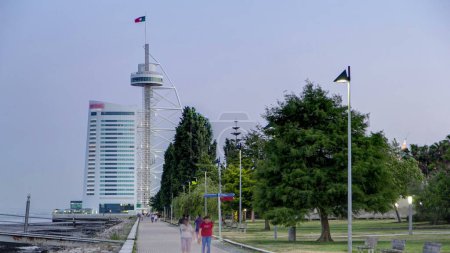 Photo for Walkway near Hotel Tower in the Park of the Nations with ebb-tide panoramic timelapse from day to night transition, lights turn on. It is 145 meters tall built over the Tagus river. Lisbon, Portugal - Royalty Free Image