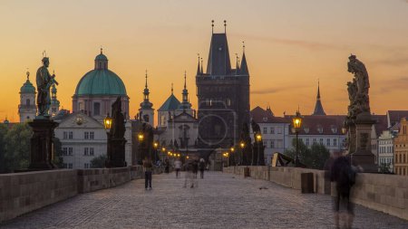 Foto de Puente de Carlos en Praga con luces de calle antes del amanecer noche a día timelapse transición, Bohemia, República Checa. Cielo naranja - Imagen libre de derechos