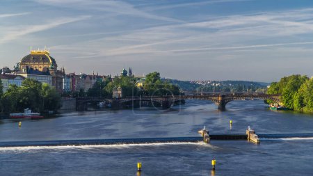 Vltava river timelapse in district Strelecky ostrov with the bridge of the Legions (Most legii) and National Theater building early morning, Prague, Czech Republic