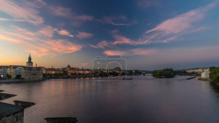 Téléchargez les photos : Vue depuis le pont Charles à Prague avant le lever du soleil nuit au jour transition timelapse, Bohême, République tchèque. Ciel nuageux coloré, reflet dans la rivière Ltava - en image libre de droit