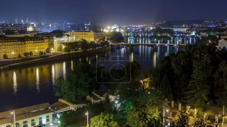 Foto de Vista panorámica de los puentes en el timelapse de la noche del río Moldava y del centro histórico de Praga: edificios y monumentos del casco antiguo con tejados rojos y paredes multicolores. - Imagen libre de derechos