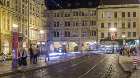 Téléchargez les photos : Vue de nuit de la place illuminée Malostranske namesti avec des personnes sur le tram arrêt timelapse à Prague. Près célèbre pour l'église de saint Nicolas. PRAGUE, RÉPUBLIQUE TCHÈQUE - en image libre de droit