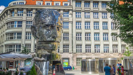 Téléchargez les photos : Monument de Franz Kafka timelapse en forme de tête gigantesque avec des segments rotatifs. Prague, République tchèque. Des gens qui marchent - en image libre de droit