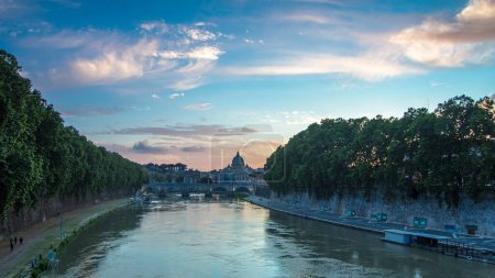 Photo for St. Peter's Basilica, Saint Angelo Bridge and Tiber River after the sunset day to night transition timelapse. View from bridge with beautiful cloudy sky. Rome, Italy - Royalty Free Image