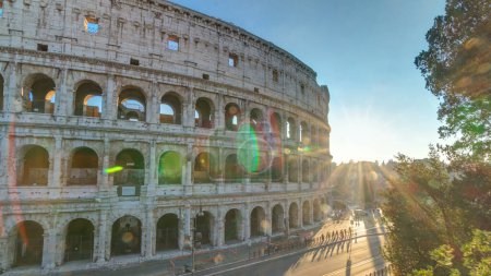 Photo for Amphitheater Colosseum view at sunset timelapse top view. Rays of setting sun in trees. Traffic on the road with bus stop. - Royalty Free Image