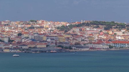 Photo for Aerial view of Lisbon over Tagus river from viewpoint of Cristo Rei in Almada with yachts tourist boats timelapse. Historic district with red roofs. Castle on the top. Lisbon, Portugal - Royalty Free Image