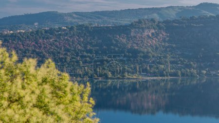Téléchargez les photos : Aube Embrace : Albano Lake Coast Panoramic Timelapse, Rome Province, Latium, Italie centrale. La lumière du matin baigne le paysage, projetant une douce lueur sur les arbres verts luxuriants - en image libre de droit