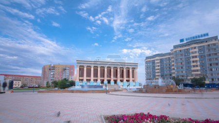Téléchargez les photos : Timelapse Hyperlapse du Théâtre Makhambet Utemissov à Atyrau City, Kazakhstan. Une journée ensoleillée dévoile le joyau culturel contre un ciel nuageux bleu - en image libre de droit