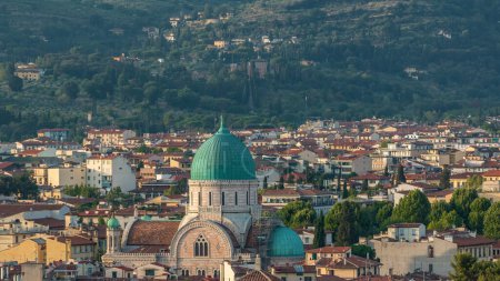 Synagogue of Florence timelapse with green copper dome rising above surrounding suburban housing with green hillside behind. Aerial top view from Michelangelo square viewpoint before sunset