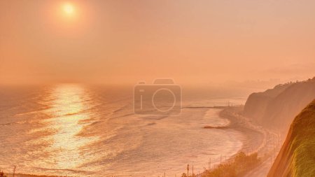 Luftaufnahme des Sonnenuntergangs von Limas Küste in der Nähe von Miraflores Zeitraffer mit orangefarbenem Licht, Lima, Peru. Straße mit Verkehr und Strand mit Meer