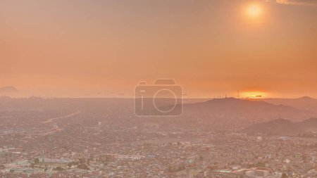 Luftaufnahme des Sonnenuntergangs von Lima Skyline Zeitraffer von San Cristobal Hügel. Verkehr auf Brücken und dem Fluss Rimac. Stadtlandschaft mit Slums und historischen Gebäuden in Südamerika. Orangener Himmel. Peru