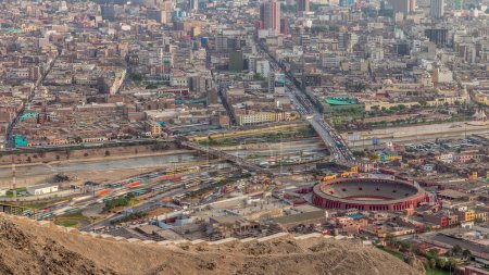 Luftaufnahme der Skyline von Lima mit der Stierkampfarena Plaza de Toros de Acho vom Hügel San Cristobal. Verkehr auf Brücken und dem Fluss Rimac. Stadtlandschaft mit Slums und historischen Gebäuden in Südamerika. Peru