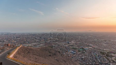 Luftaufnahme der Skyline von Lima Tag und Nacht Übergang von San Cristobal Hügel. Verkehr auf Brücken und dem Fluss Rimac. Landschaft von Slumsiedlungen mit historischen Gebäuden und Wolkenkratzern in Südamerika. Peru