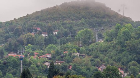 Casas en una colina con teleférico que sube y baja de la estación de Sarajevo a las montañas, Bosnia y Herzegovina. Casas con techos rojos y árboles verdes
