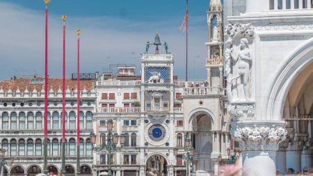 Photo for St Mark's Clock tower timelapse on Piazza San Marco, facade, Venice, Italy. Tourists on the square. On the facade of the tower is the astronomical clock. At the top is a bell and Moors figures - Royalty Free Image