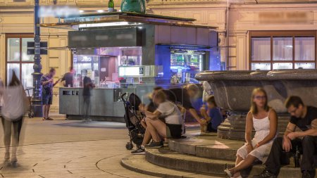 Foto de Quiosco de comida callejera y quiosco de salchichas noche timelapse en Viena. Gente comprando comida con bebidas y comiendo por ahí - Imagen libre de derechos