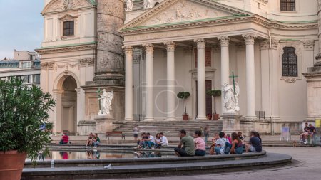 Foto de Karlskirche en el timelapse cuadrado de Karlsplatz en Viena, Austria. Gente caminando y sentada en la fuente. Es una iglesia católica, también llamada Rektoratskirche, con una arquitectura barroca típica
. - Imagen libre de derechos