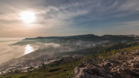 Panorama mit Luftaufnahme der Stadt und des Hafens von Sesimbra, Portugal. Top Landschaft über den Wolken und untergehende Sonne. Resort im Distrikt Setubal