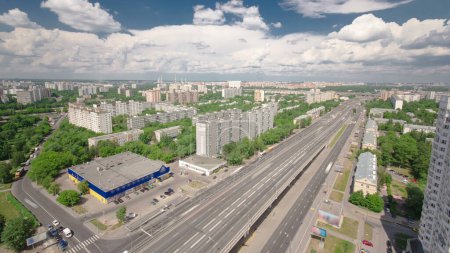 Blick von oben auf den Verkehr auf der Hochstraße im Zeitraffer auf der Autobahn Jaroslawl in Moskau, Russland. Panorama mit vielen Häusern und grünen Bäumen