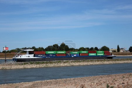 Téléchargez les photos : Transport de conteneurs par voie navigable sur la rivière Waal devant la ville de Tiel aux Pays-Bas - en image libre de droit