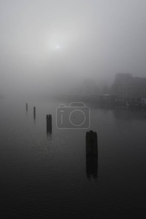 Téléchargez les photos : Rivière Amstel à Amsterdam avec péniches et maisons dans un brouillard dense - en image libre de droit