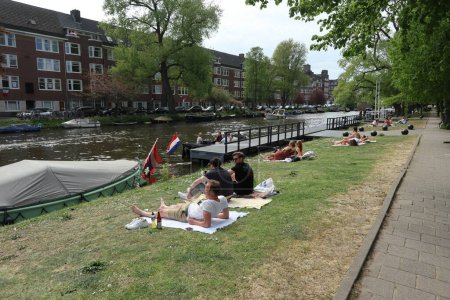 Téléchargez les photos : Les gens de loisirs dans l'herbe le long de l'Amstelkade à Amsterdam, aux Pays-Bas - en image libre de droit