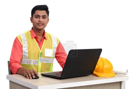 Téléchargez les photos : Architecte indien mâle regardant la caméra tout en travaillant avec un ordinateur portable dans le bureau - en image libre de droit