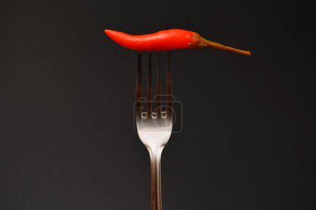 hot chili peppers on a fork on a dark background close-up
