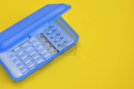 Foto de Blue box with pills on yellow background, copy space - Imagen libre de derechos