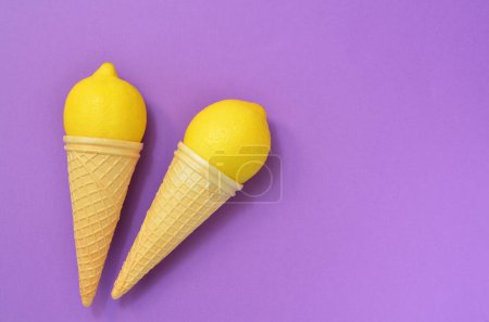 Foto de Limones maduros en conos de gofre sobre un fondo púrpura, espacio de copia, disposición plana - Imagen libre de derechos