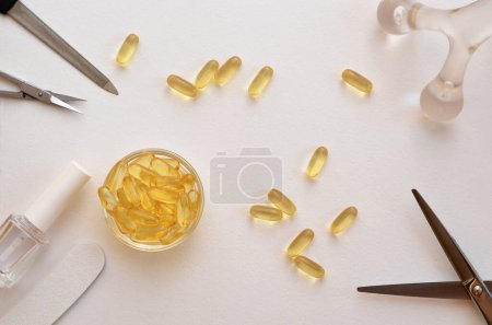 Foto de Cápsulas y herramientas omega-3 para el cuidado de uñas, piel y cabello, tijeras, lima de uñas y esmalte de uñas - Imagen libre de derechos