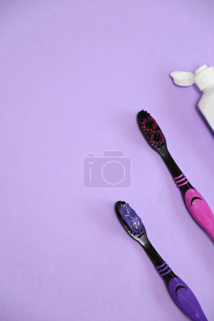 Téléchargez les photos : Brosses à dents et dentifrice violet sur fond lilas, espace de copie plat - en image libre de droit