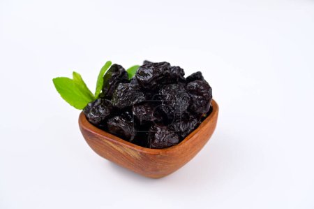 natural dried prunes in wooden bowl isolated on white background