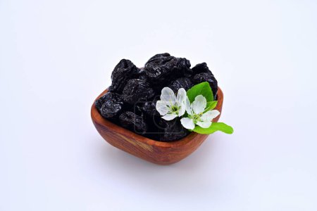 bowl with prunes and plum flowers on a white background