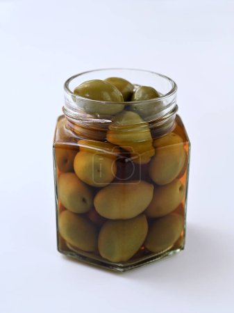 Glas mit grünen Oliven in Salzlake auf weißem Hintergrund Nahaufnahme