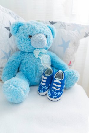 Photo for Childrens bed with a teddy blue bear and childrens small shoes nearby, childrens room interior. Childrens accessories. - Royalty Free Image