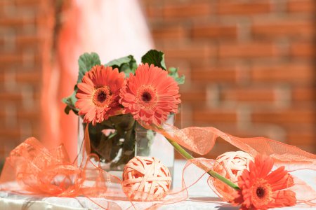 Photo for Decor of ribbons and gerbera flowers in the color Apricot Crush - the color of the next 2024 according to Pantone, close-up. - Royalty Free Image