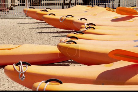 Téléchargez les photos : Groupe de kayaks de dériveur imperméables alignés dans la couleur de l'année écraser abricot. Bateaux de sport sur la côte close-up. - en image libre de droit