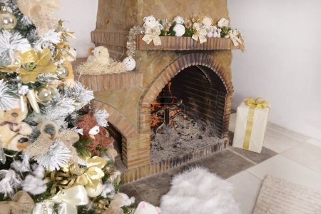Téléchargez les photos : .Fond de Noël, arbre de Noël décoré avec des jouets et des boules de verre près d'une cheminée en pierre avec guirlande décorative de sapin de Noël et feu ardent, tapis molletonné chaud.Intérieur de la maison de Noël - en image libre de droit