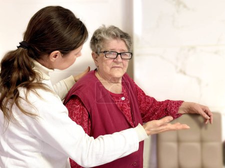 Téléchargez les photos : Un travailleur social attentionné montre et explique quelque chose à une femme âgée par des gestes de main. Concept de soutien et de compréhension - en image libre de droit