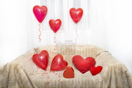 Festive background for lovers on Valentine's Day, wedding, anniversary, birthday from a sofa decorated with pillows and heart-shaped balloons