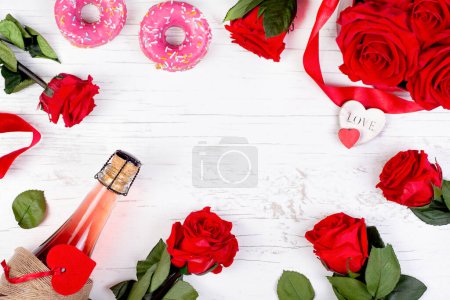 background for Valentine's day with a bottle of champagne, heart, red roses, sweets donuts on a wooden background. Greeting invitation card, mockup for wedding, birthday