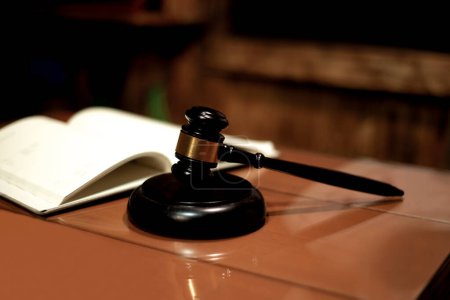 Photo for Judicial gavel HAMMER years on a backing on a wooden table against the background of an open magazine book out of focus, close-up, selective focus - Royalty Free Image