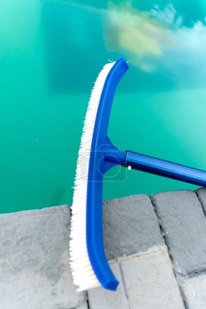 Handheld cleaner large brush next to the pool. Cleaning service. Preparation for summer season.