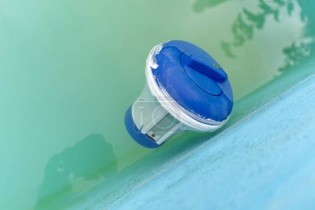 Détermination de l'alcalinité de l'eau dans la piscine, appareil de filtration, chlorateur, thermomètre à eau flotte dans l'eau de la piscine.