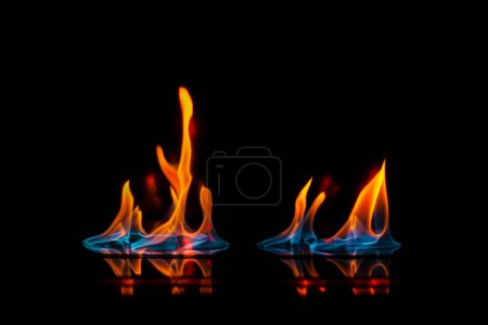 Foto de Llama intensa, fuego, ardiendo brillantemente sobre un fondo oscuro, sobre una superficie de espejo con reflejo, peligro, catastrófico - Imagen libre de derechos