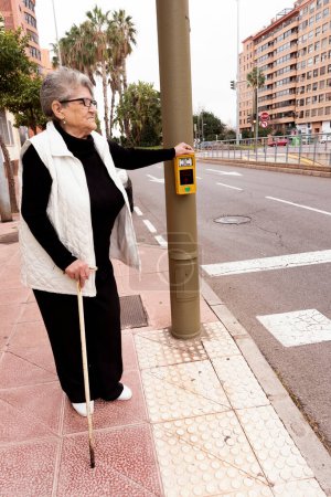 Un vieil homme utilise un bouton de passage piétonnier dans une rue de la ville. Smart city, confort et technologies de sécurité